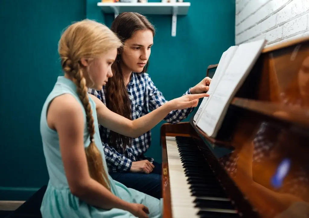 Learn How To Track Your Progress! VAMPR Academy is the future of music education and is crucial if you want to make it in the industry! Get started today! Piano teacher giving a music lesson to her student, explaining notes, home studying By Artranq