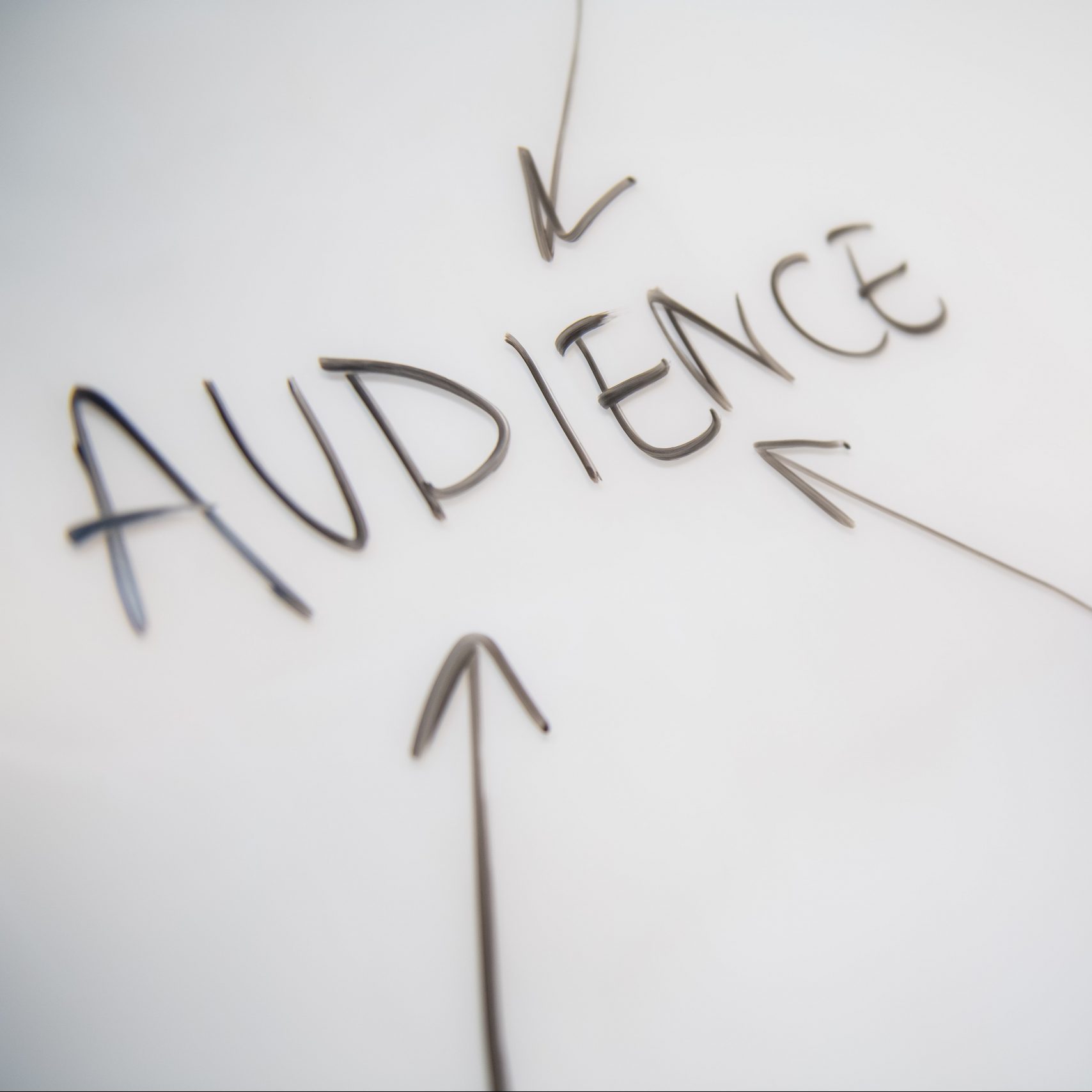 The word audience on a white board in black marker with three black arrows pointing inwards to the word.