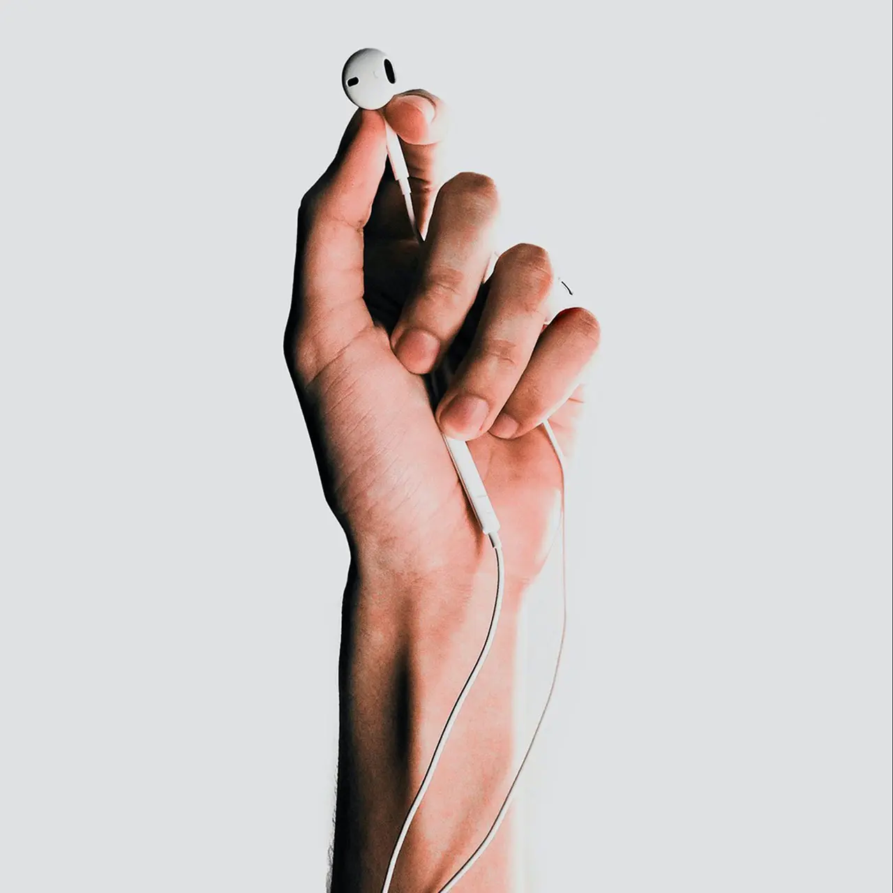 hand holding white apple earphones. White background.