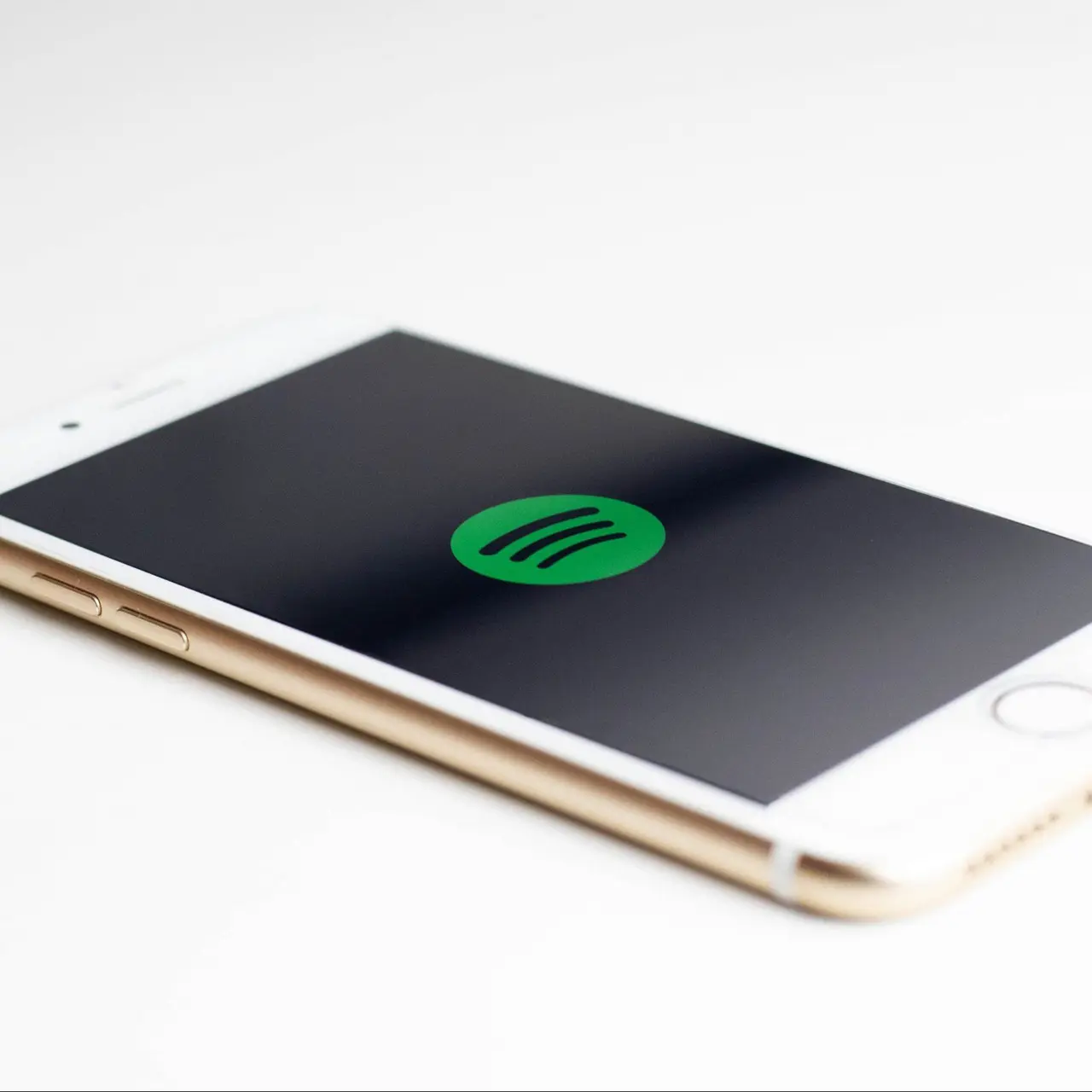 white iphone with a black screen and green spotify logo in the center.