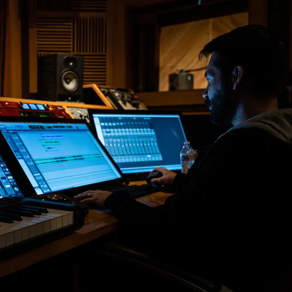 A music producer works on a digital audio workstation in a studio, showcasing top sync licensing platforms.