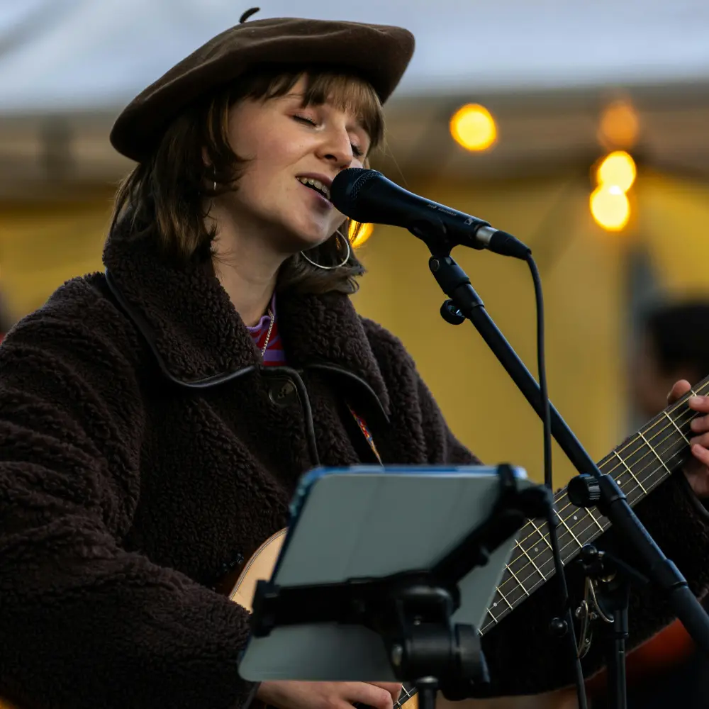 Music discovery through A&R thrives on unique styles, as seen in this artist passionately singing and playing guitar at an intimate event.