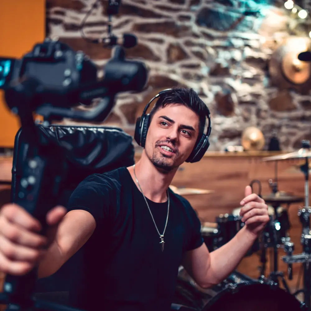 A musician wearing headphones recording a video in a studio, showcasing indie music promotion through content creation.