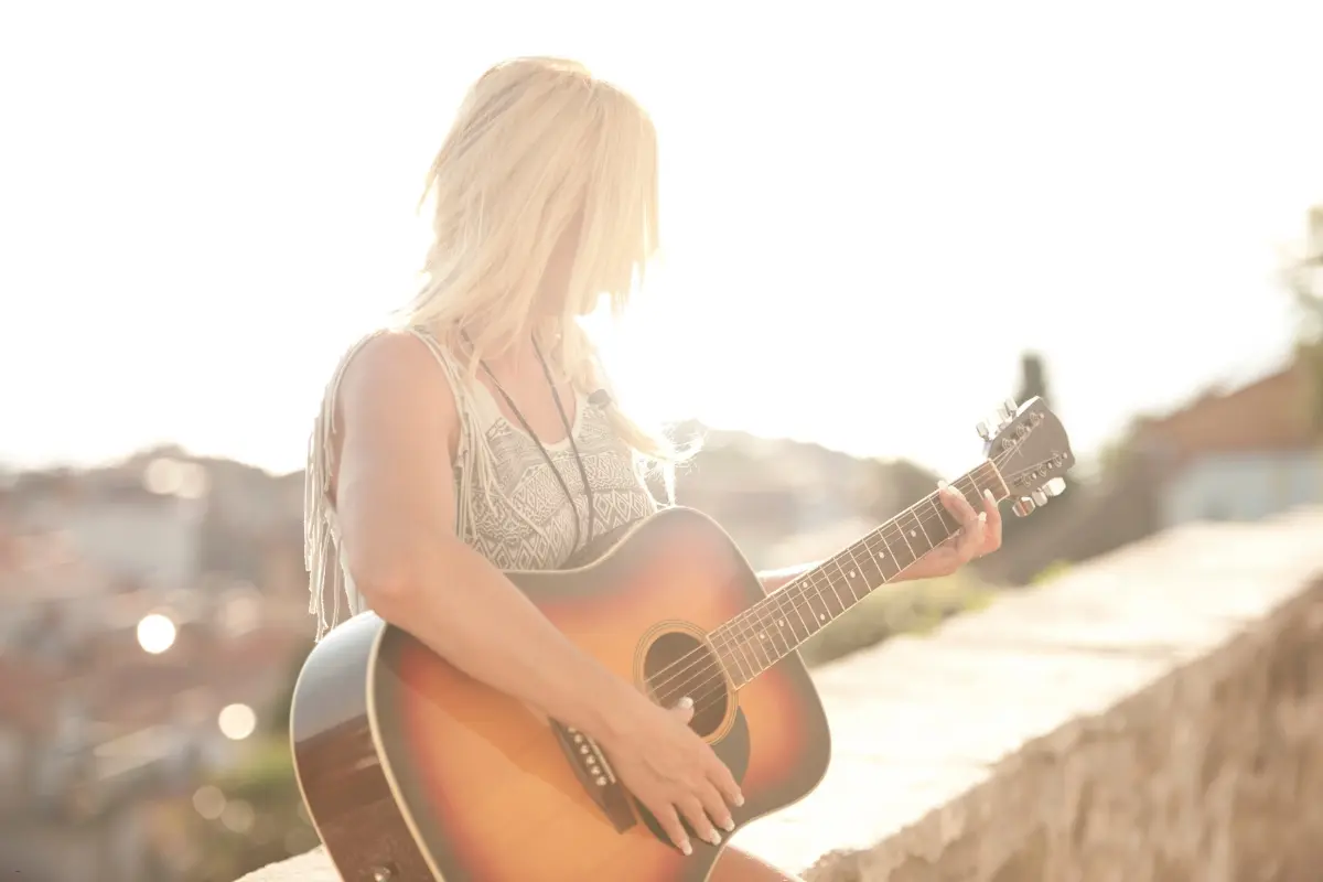 A guitarist playing outdoors in warm sunlight, demonstrating independent artists using music promotion tools to reach audiences.