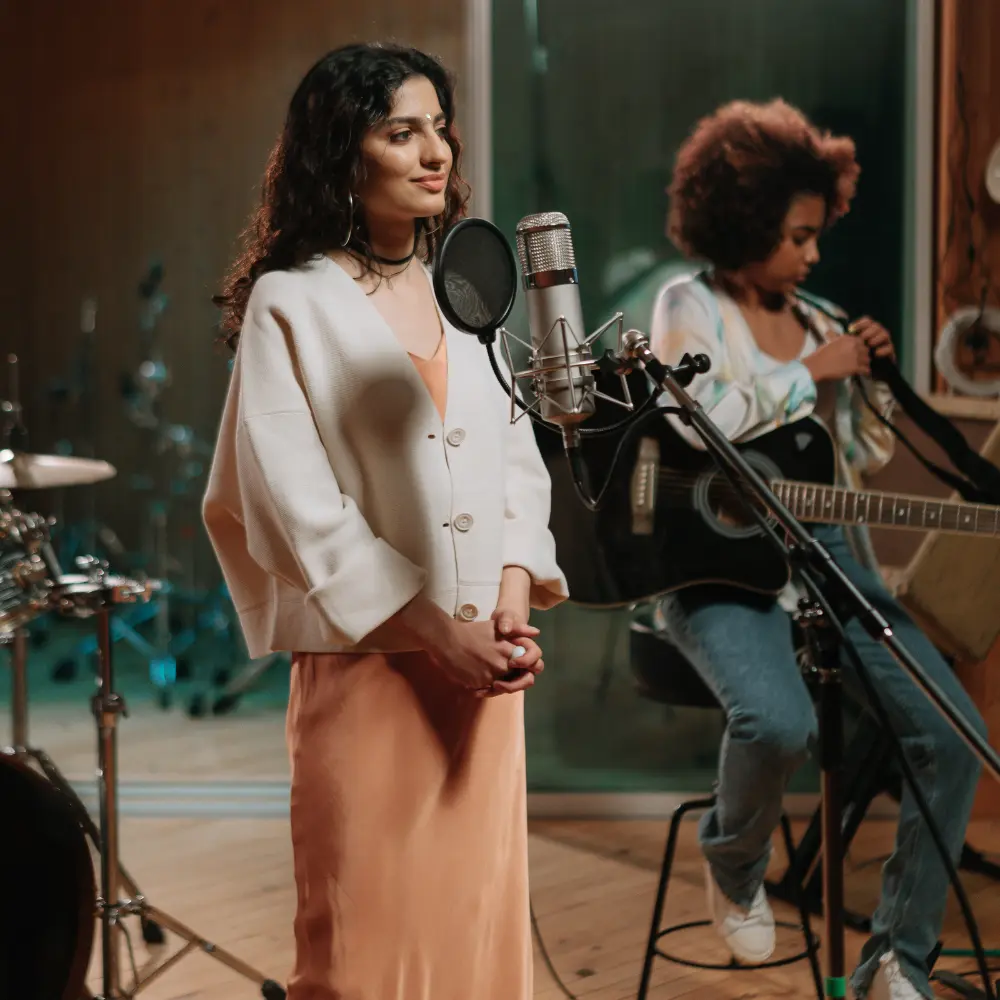 A female vocalist performs in a recording studio with a guitarist, emphasizing self-publishing opportunities for musicians.