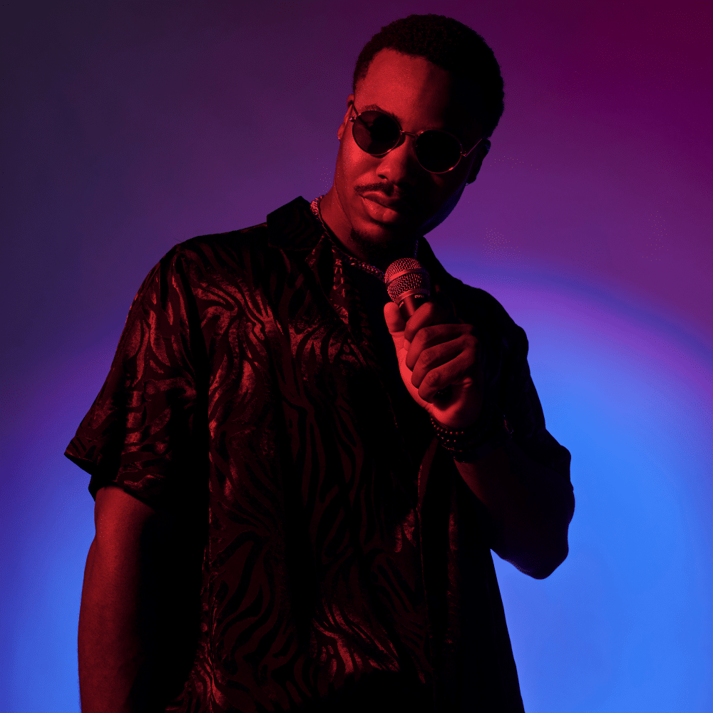 A male artist in sunglasses performs under moody lighting, representing music distribution services for independent musicians.