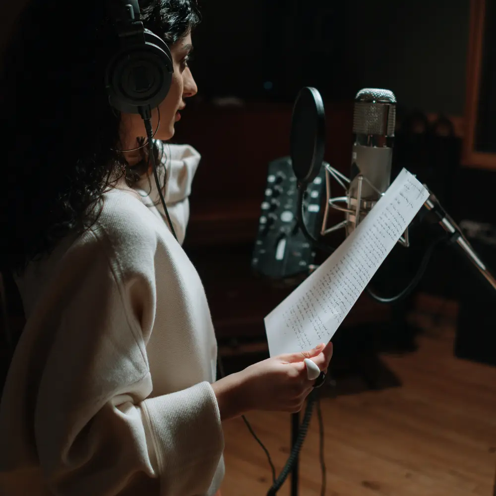 A female artist records vocals in a studio, representing personal branding and image development for musicians.