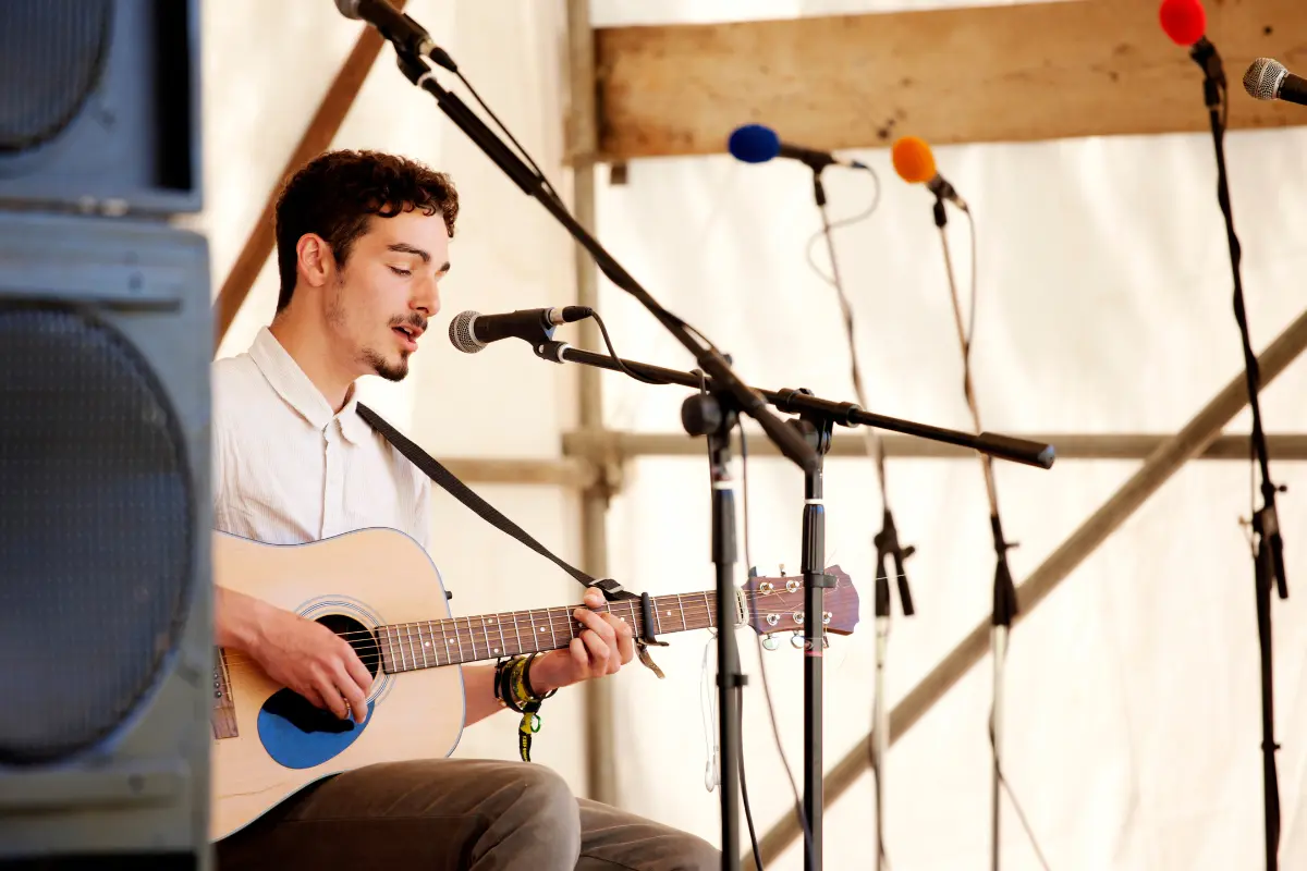 Professional music profile represented by a solo acoustic artist performing live at a small venue