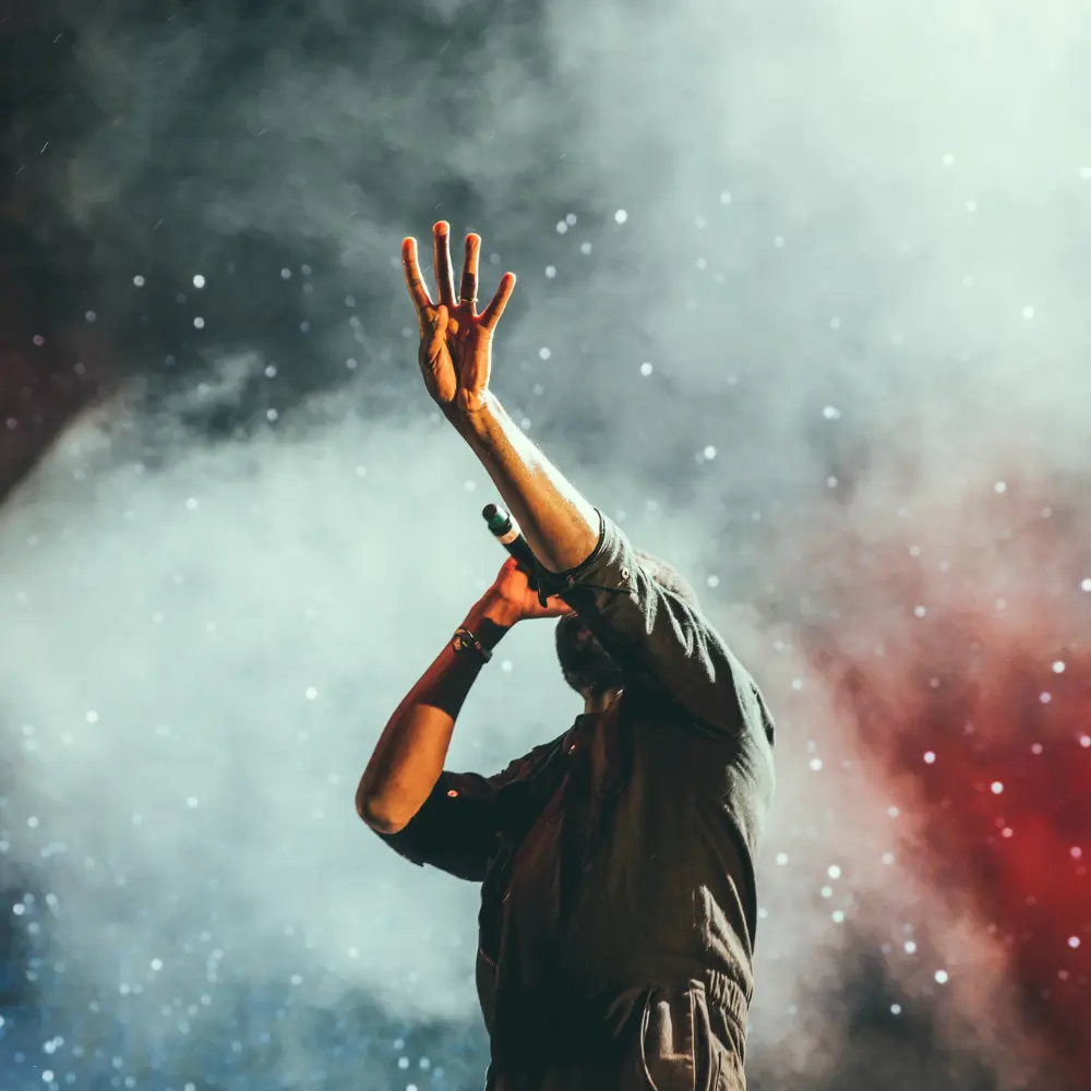 Creative freedom in music expressed by a dynamic solo performer gesturing powerfully on a foggy concert stage