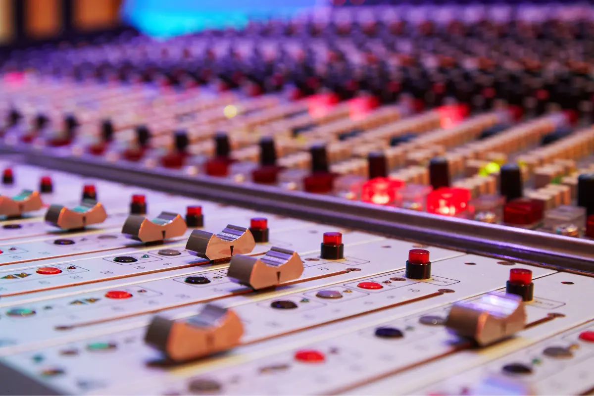 Digital music royalties illustrated by a close-up of an illuminated audio mixing console in a recording studio