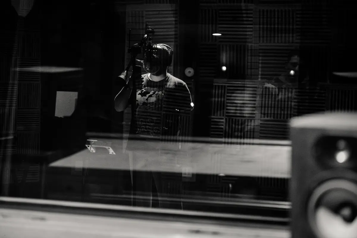 Music business for artists shown through a solo musician recording in a soundproof professional studio booth