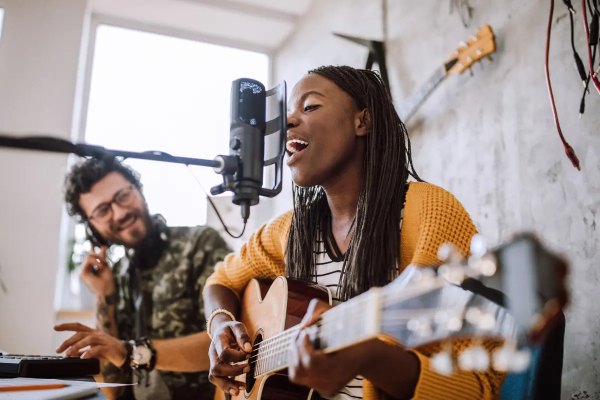 Music partnership ideas reflected in a joyful duo recording vocals and guitar in a home studio setup